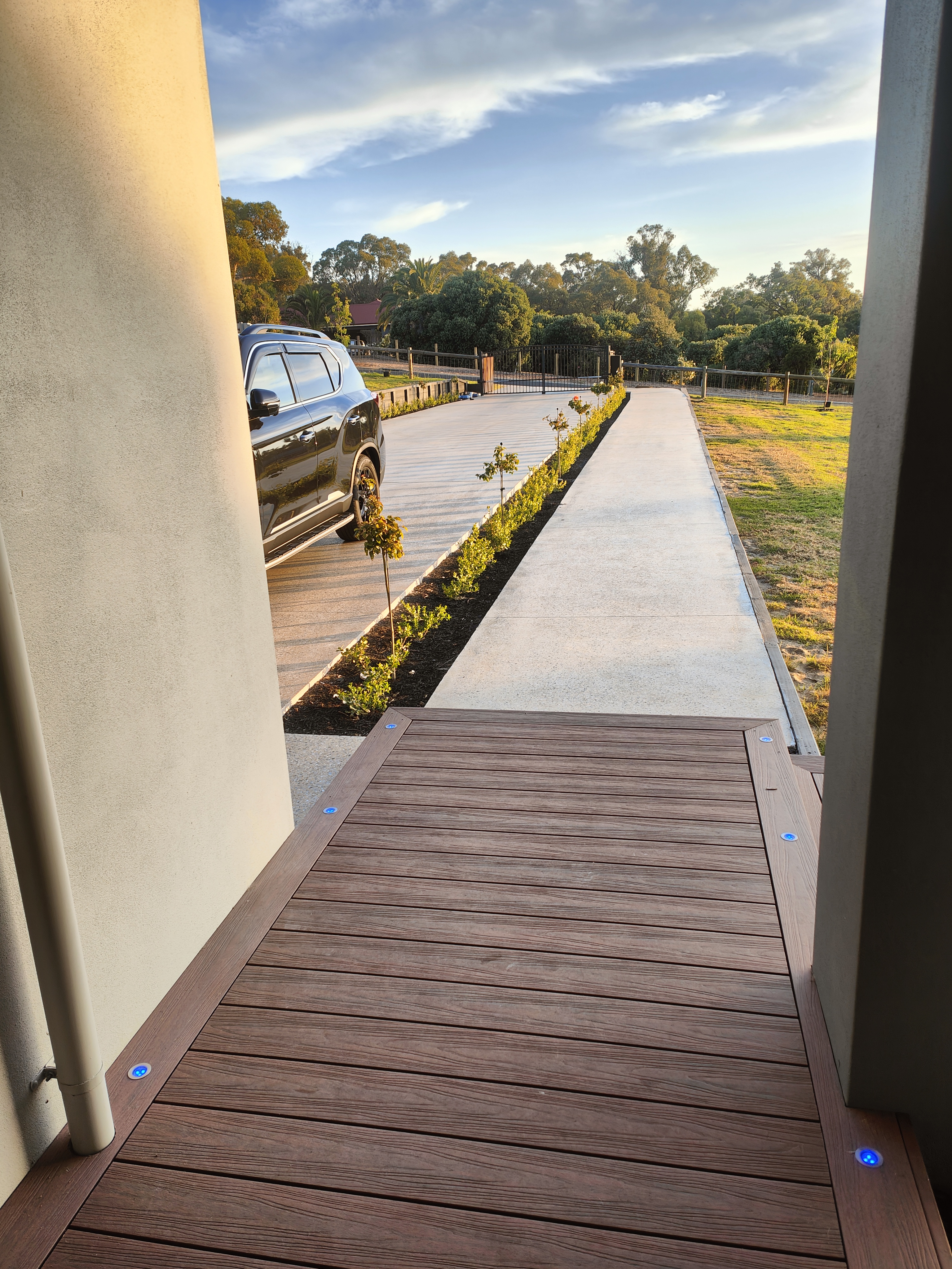 Composite deck and honed concrete driveway at sunset — Element Structures project